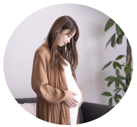 お腹に手を添えて微笑む妊娠中の女性